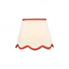 A neutral scalloped edge table lamp shade with red accent edging